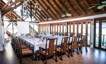 a large dining room with a long table set for a formal event , complete with chairs , flowers , and a chandelier at Anantara Dhigu Maldives