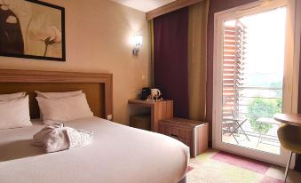 a hotel room with a large bed , a chair , and a window overlooking the city at Mercure Libourne Saint Emilion