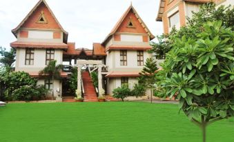 a large house with a red roof and white walls is surrounded by green grass at Aalankrita Resort and Convention