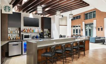 a modern bar area with a long counter , several chairs , and a television mounted on the wall at Hyatt Place Melbourne / Palm Bay / I-95