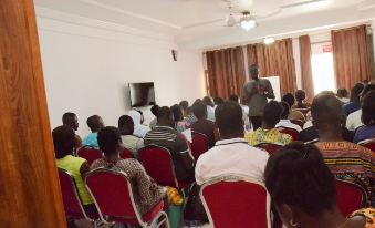 a group of people gathered in a room , listening to a man who is giving a presentation at Ibisa Hotel