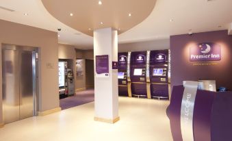 a modern office interior with purple walls , white ceiling , and several display cabinets , including a welcome sign at Premier Inn Rochester
