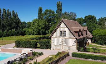 a beautiful french - style house with a thatched roof , surrounded by lush green trees and grass at Les Manoirs des Portes de Deauville - Small Luxury Hotel of the World