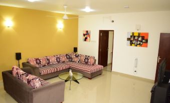 a living room with a yellow wall , pink and gray couches , and a glass coffee table at Click to Go