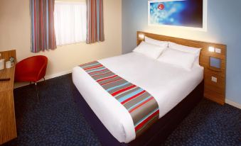 a hotel room with a large bed , white sheets , and colorful bedding , along with other furniture and decorations at Travelodge Scotch Corner Skeeby
