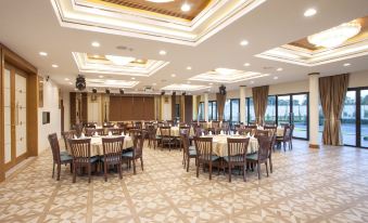 a large , well - lit dining room with multiple tables and chairs arranged for a group of people to enjoy a meal at RK Riverside Resort & Spa (Reon Kruewal)