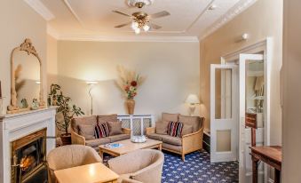 a cozy living room with several chairs arranged around a coffee table , creating a comfortable space for relaxation at Best Western New Holmwood Hotel
