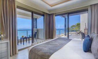 a bedroom with a large bed and sliding glass doors leading to an ocean view balcony at Royalton Negril, An Autograph Collection All-Inclusive Resort