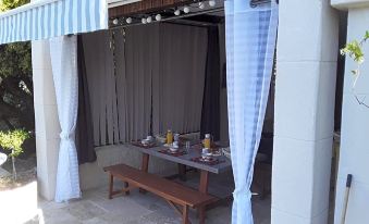 a wooden table with a bench underneath it is set up under a covered patio area at L'Atelier