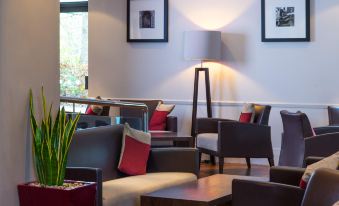 a modern living room with several chairs and couches arranged around a coffee table , creating a comfortable seating area at Holiday Inn Express Droitwich Spa