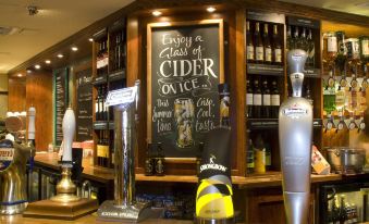 "a bar with a chalkboard sign that reads "" for a social event , enjoy a cold cider on ice ."" the bar is stocked" at Premier Inn Hull West