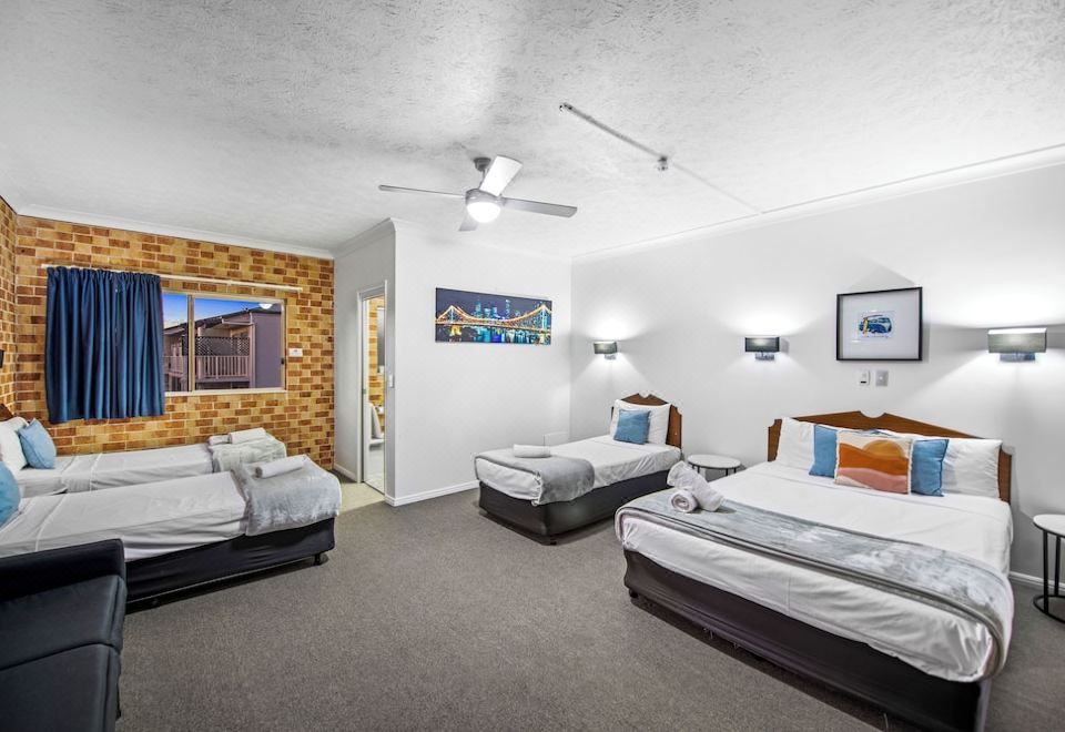 a hotel room with three beds , one on the left , one in the middle , and one on the right at Airport Clayfield Motel