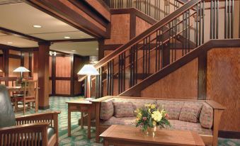 a spacious , well - lit room with a large couch , wooden coffee table , and stairs leading to the upper level at The Craftsman Inn & Suites