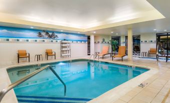 a large swimming pool with a ladder and lounge chairs is surrounded by chairs and tables at Courtyard Danbury