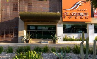 "a building with a large orange sign that says "" st . georges "" is surrounded by plants and cacti" at Hotel St. George