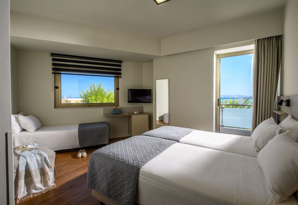 a hotel room with two beds , a window offering a view of the ocean , and a desk at Marin Hotel