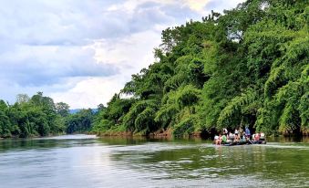 a group of people are on a boat , navigating through a lush green river surrounded by trees at Baan Rai Darun Home Stay and Scenery Raft