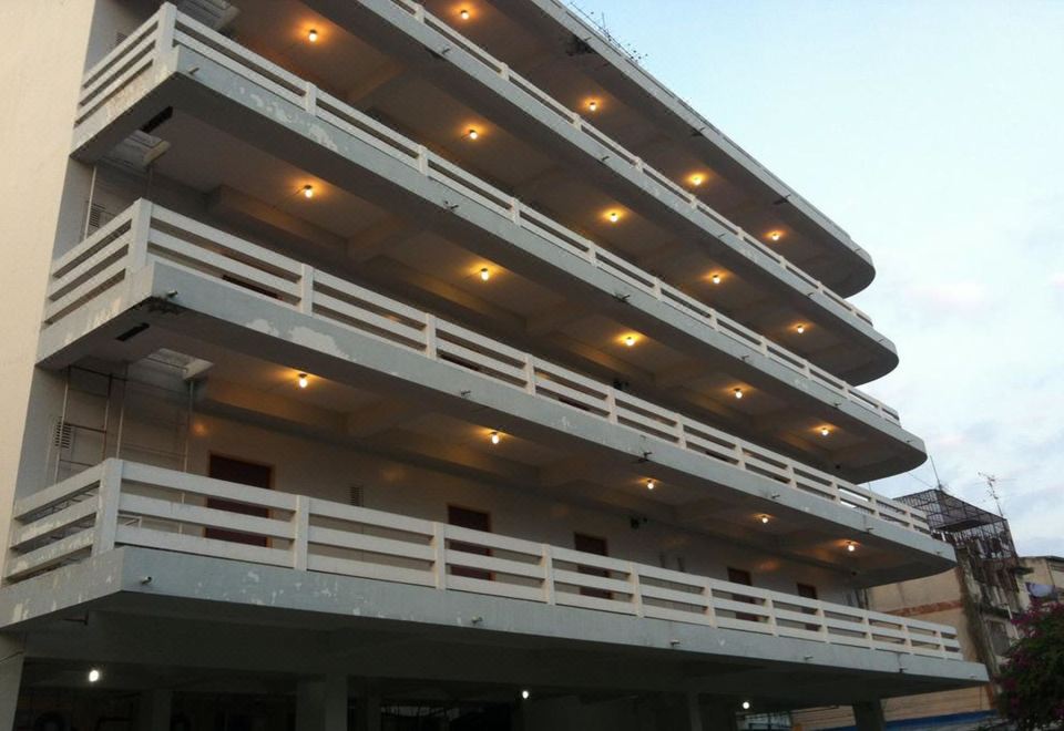 a multi - story building with white balconies and orange lights is shown against a blue sky at Sakol Hotel