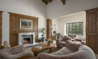 a cozy living room with a fireplace , wooden furniture , and a large window overlooking the outdoors at The Inn at Rancho Santa Fe