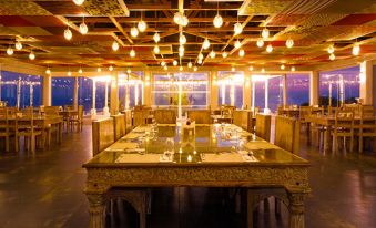 a large , well - lit restaurant with multiple dining tables and chairs , all set for a formal dinner at Serena Beach Resort