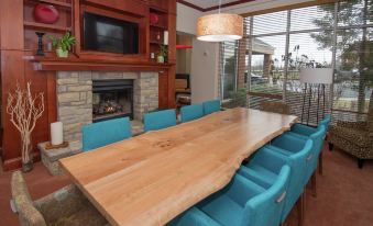 a wooden dining table surrounded by blue chairs with a fireplace in the background , creating a warm and inviting atmosphere at Hilton Garden Inn Lexington/Georgetown
