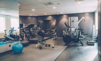 a well - equipped gym with various exercise equipment , including treadmills and weightlifting machines , in a well - lit room at Radisson Blu Waterfront Hotel, Stockholm