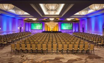 a large conference room with rows of chairs and a stage at the front , illuminated by purple lights at The Westin Rancho Mirage Golf Resort & Spa