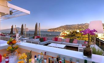 a rooftop bar with a view of the ocean and city , featuring white lounge chairs and tables at Hotel Continental