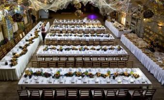 a large banquet hall is set up with long tables covered in white tablecloths and decorated with flowers at Hotel Boss