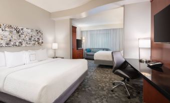 a modern hotel room with a bed , couch , and chair , as well as a large window at Courtyard Pittsburgh Washington/Meadow Lands