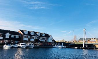 a boat is docked at a pier next to a row of houses on the water at Hotel Wroxham