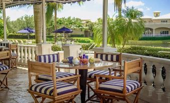 a table with blue and white striped chairs is set up on a patio overlooking a pool at Inn at Pelican Bay