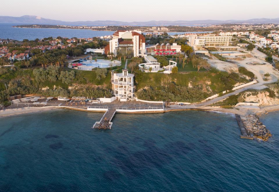 an aerial view of a residential area near a body of water , featuring a white building on the shore at Grand Hotel Ontur Cesme