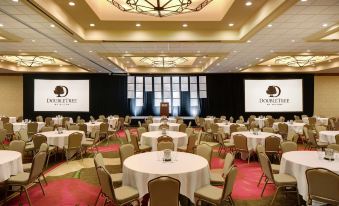 a large , well - lit conference room with multiple round tables and chairs set up for a meeting at DoubleTree by Hilton Seattle Airport