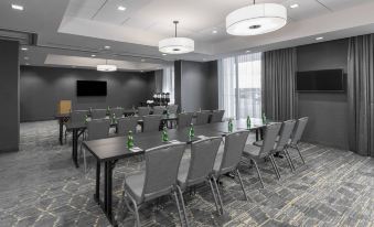 a conference room with rows of tables and chairs , a large screen on the wall , and pendant lights at Residence Inn Halifax Dartmouth