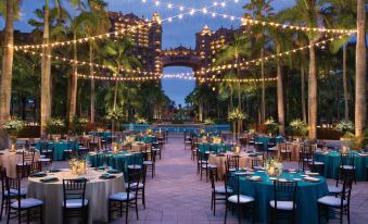a beautifully set outdoor dining area with multiple tables and chairs arranged for a formal event at The Royal at Atlantis