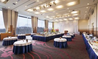 a large dining room with tables and chairs set up for a formal event , possibly a wedding reception at Hakodate-Onuma Prince Hotel