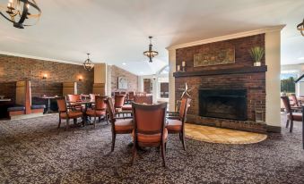 a spacious dining room with several chairs and tables , a fireplace in the background , and hanging lamps at Best Western University Inn