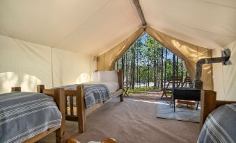 a large tent with a bed and two chairs inside , providing a cozy and comfortable setting at Under Canvas Mount Rushmore
