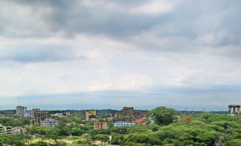 a cityscape with a cloudy sky , surrounded by trees and buildings , under a dark blue sky at Richmond Hotel Sylhet