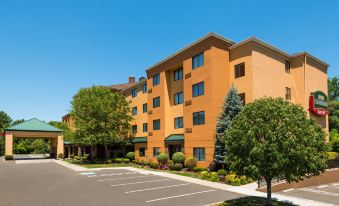 a large orange building with green awnings and trees in front of a parking lot at Courtyard Danbury