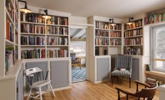 a cozy living room with a couch , chairs , and bookshelves filled with books , creating a warm and inviting atmosphere at The Deers Head Inn Tavern