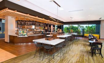 a modern restaurant with wooden floors , white tables and black chairs , and a large window overlooking trees at Courtyard Redwood City