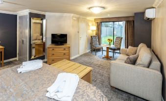 a modern living room with a bed , couch , and dining table , along with a tv and other furniture at Cbh Park Farm Hotel
