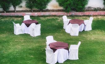 a set of white chairs and tables with burgundy tablecloths are set up on a grassy area at Hotel Empire