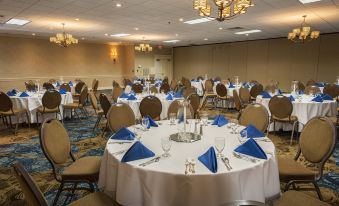 a large banquet hall with multiple round tables set for a formal event , featuring blue napkins and white tablecloths at Best Western Plus Strongsville Cleveland
