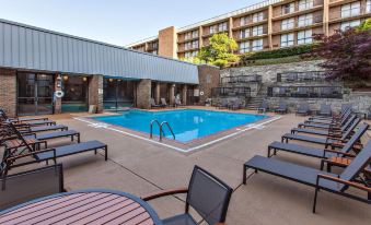 a large outdoor swimming pool surrounded by lounge chairs and tables , with a building in the background at DoubleTree by Hilton Hotel Pittsburgh - Green Tree