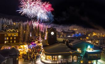 a nighttime scene with a large group of people gathered around a clock tower , watching fireworks at Sundance Resort