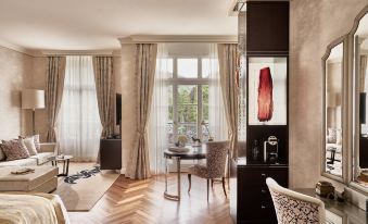 a luxurious living room with hardwood floors , large windows , and a dining table surrounded by chairs at Grand Resort Bad Ragaz