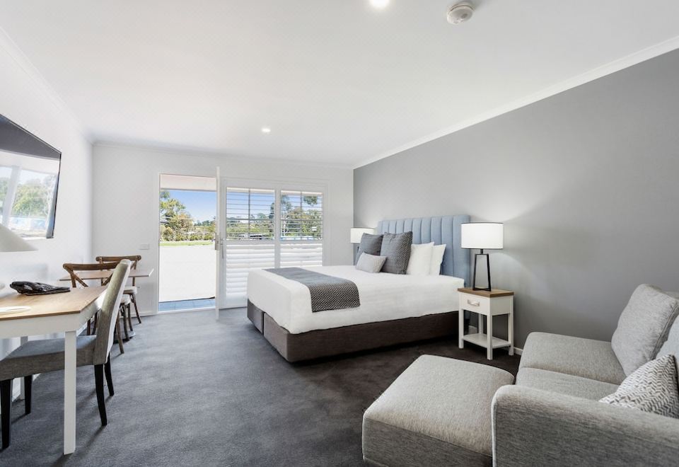 a modern bedroom with a large bed , a chair , and a window overlooking a pool at Sanctuary Inn on Westernport